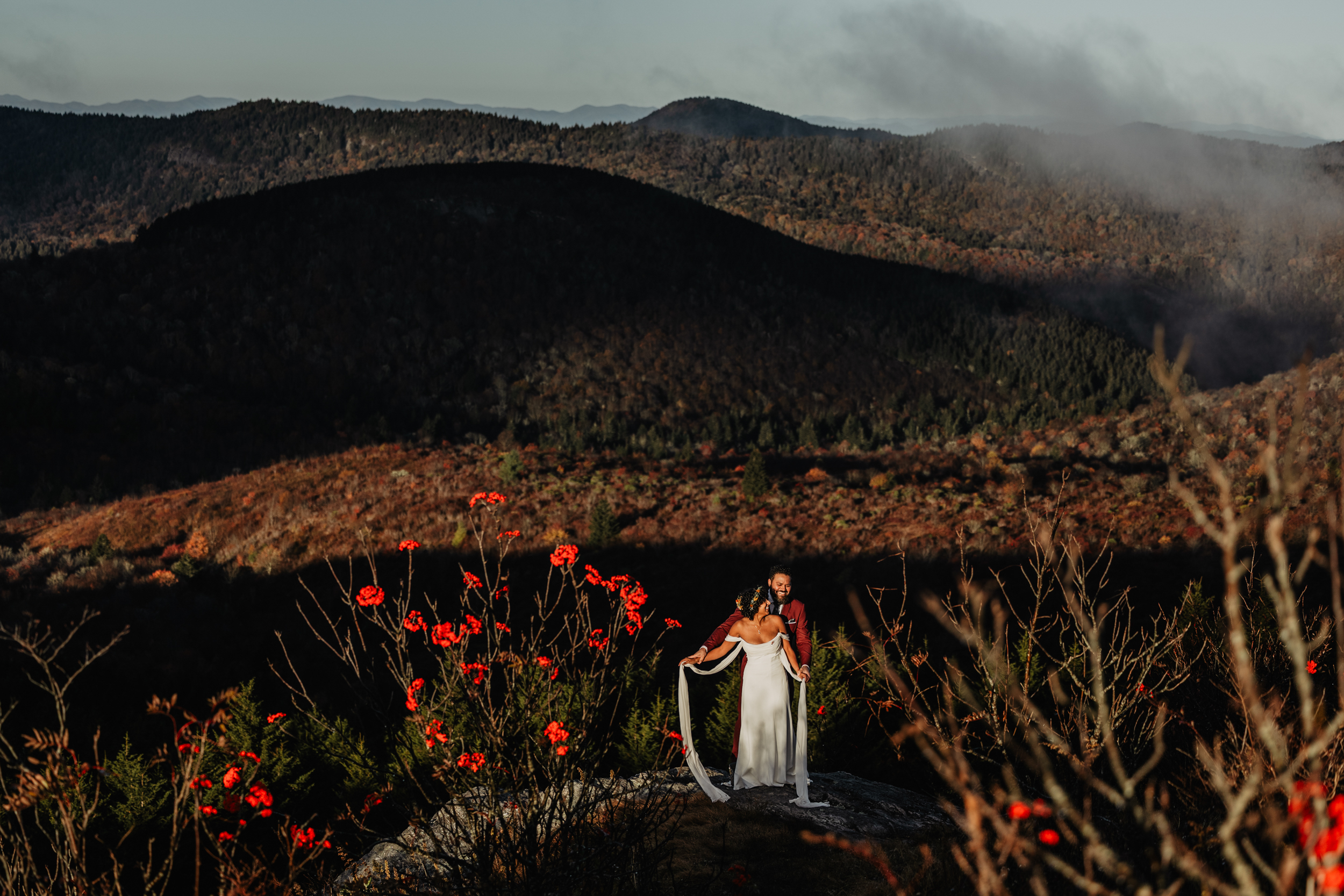 Wedding couple standing on edge of cliff for their adventure elopement in Blue Ridge Mountains